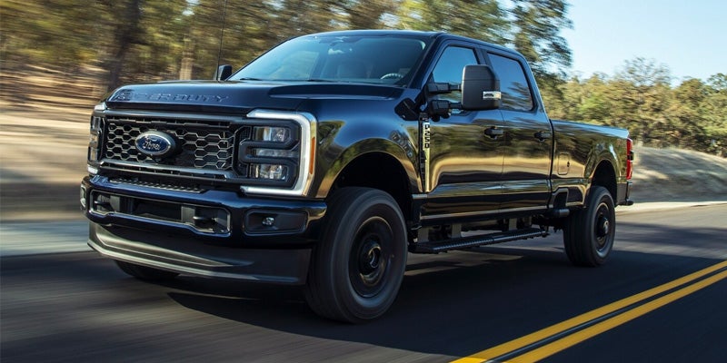 Black Ford F-250 Super Duty driving down the highway on a sunny day